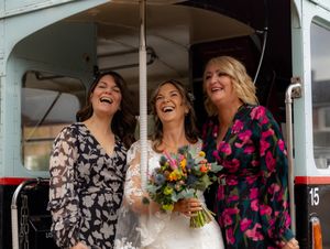 A group of wedding guests share a candid moment of laughter together under a covered porch area.