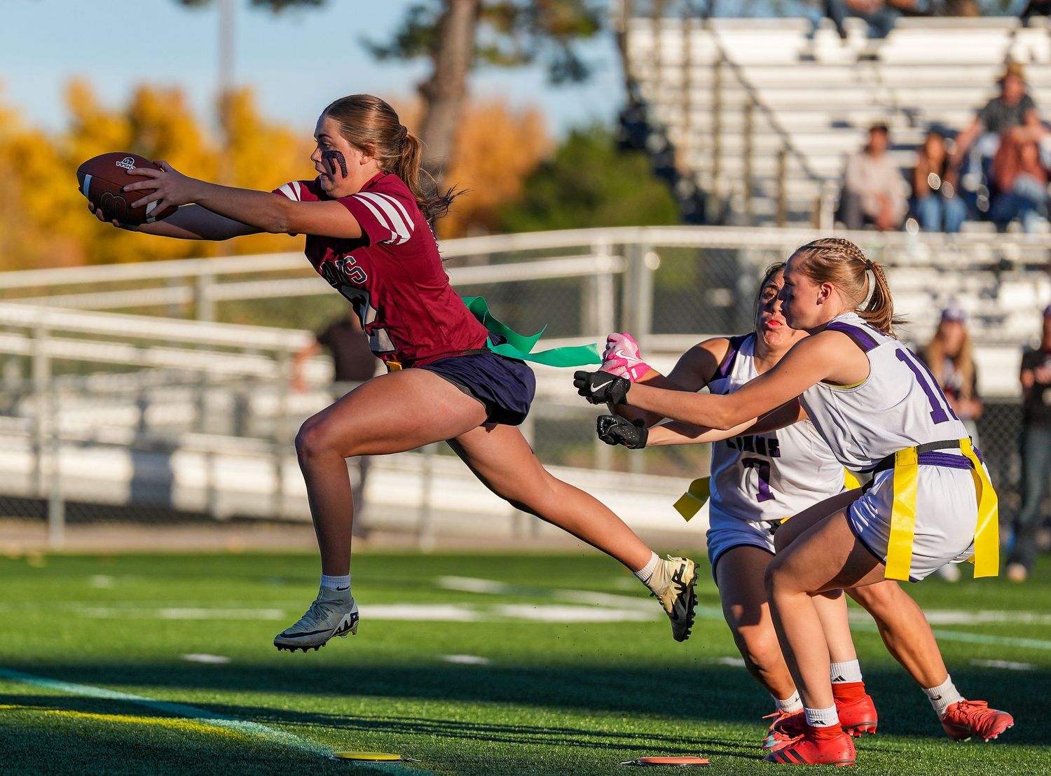 Field hockey player dives to make a defensive play during an intense match on a sunny day.