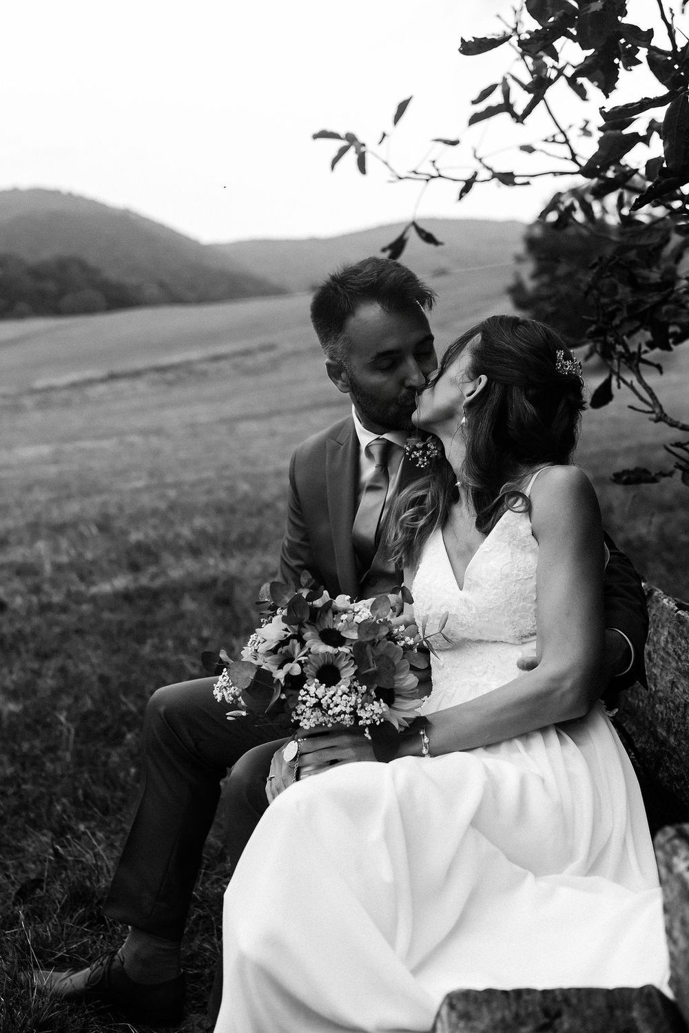 A romantic black and white wedding photo series showing a couple sharing intimate moments in a mountain landscape.
