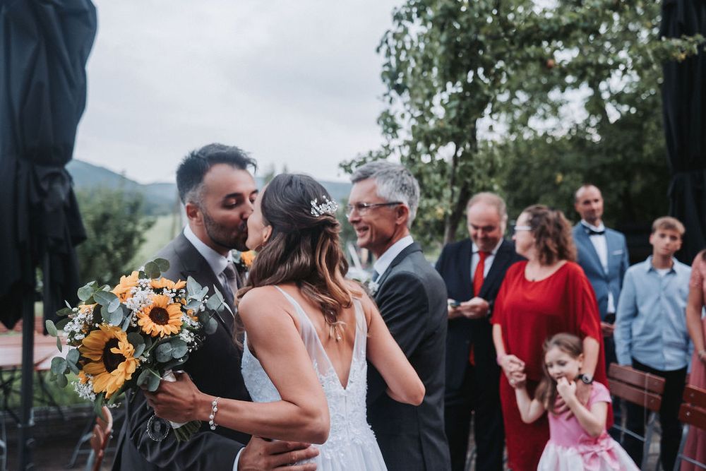 Wedding celebration outdoors with guests gathering around a couple during a summer evening reception.