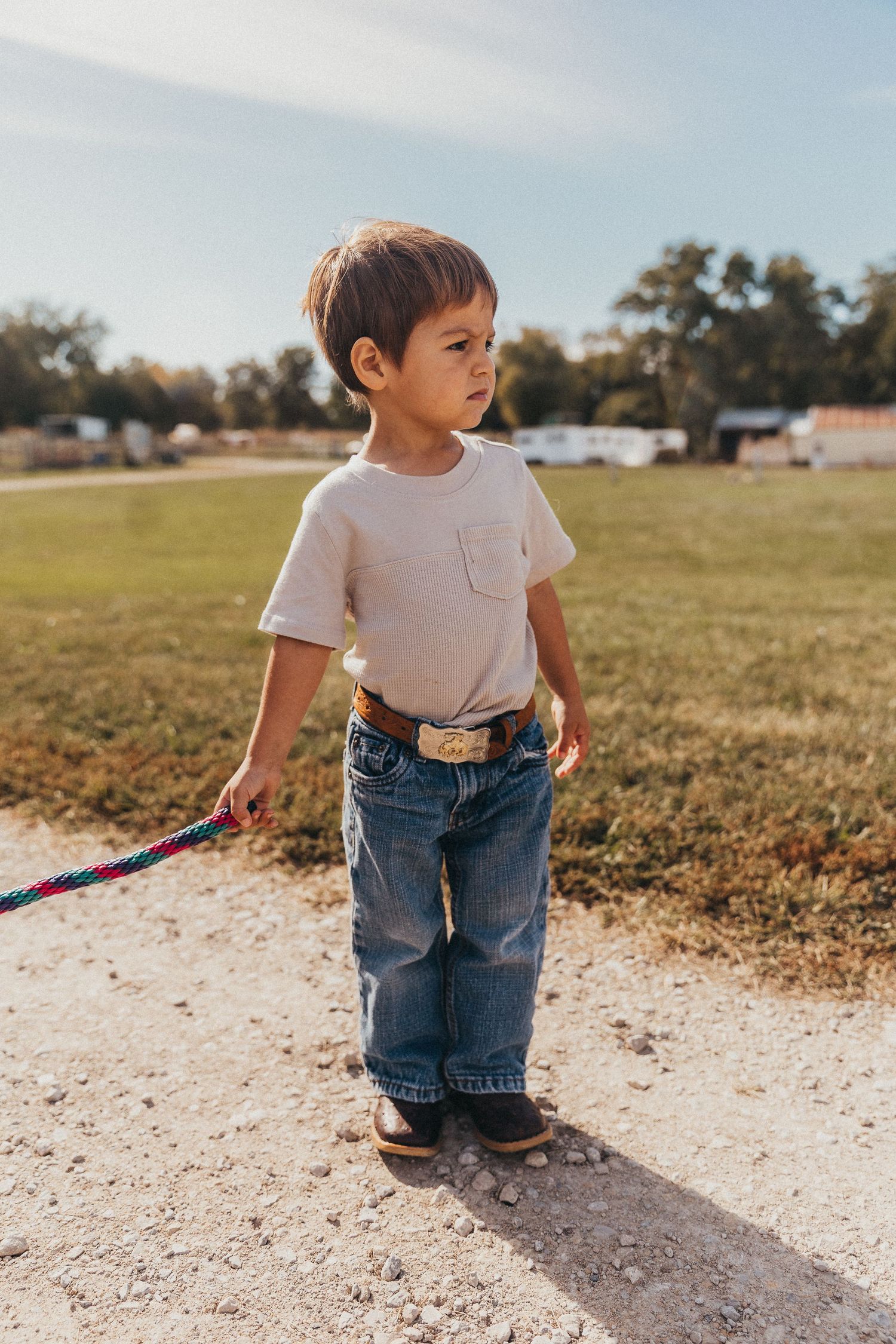 Boy standing outside holding a rope