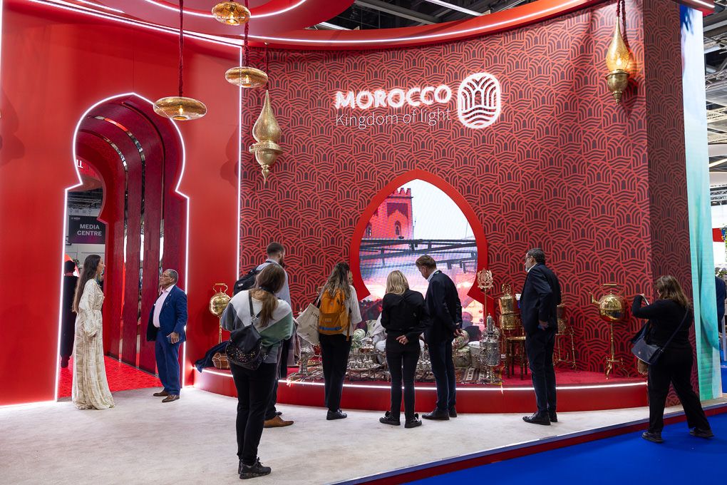 Red-walled exhibition space showcasing Moroccan cultural displays with golden decorative elements and visitors exploring the WTM, London.