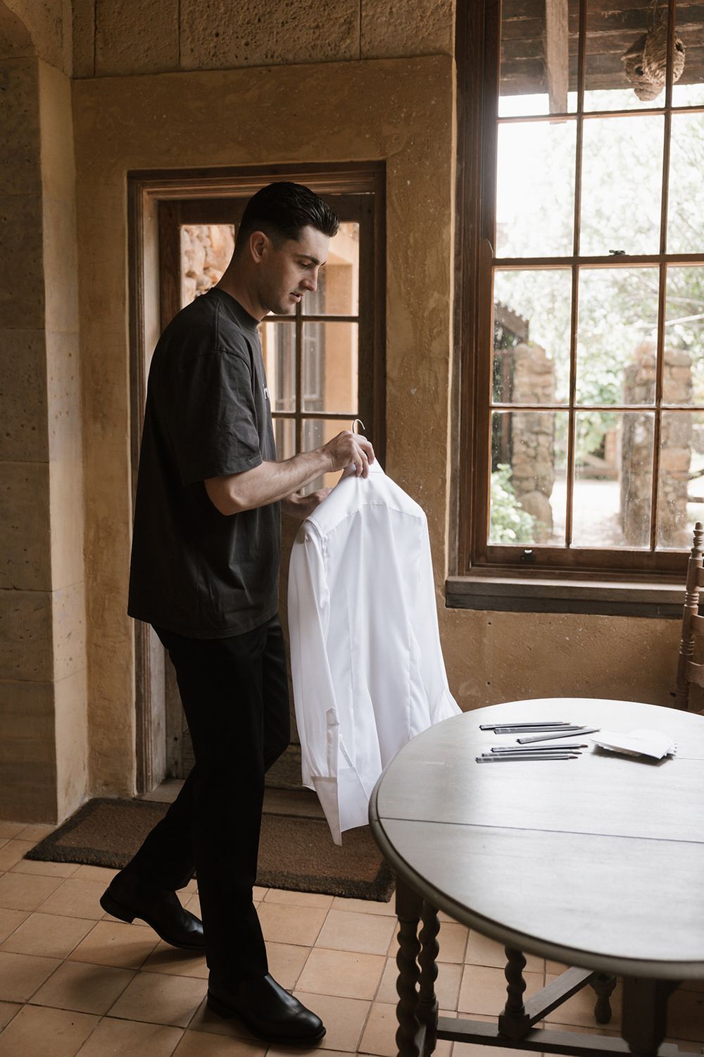 A series of photos showing someone in black clothing setting up a white backdrop or fabric in a room with large windows.