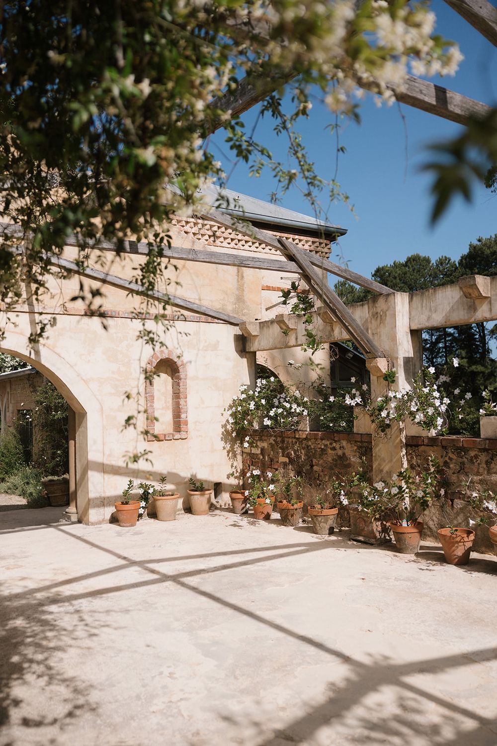 A series of outdoor patio views showing stone walls and potted plants casting shadows in Mediterranean sunlight.