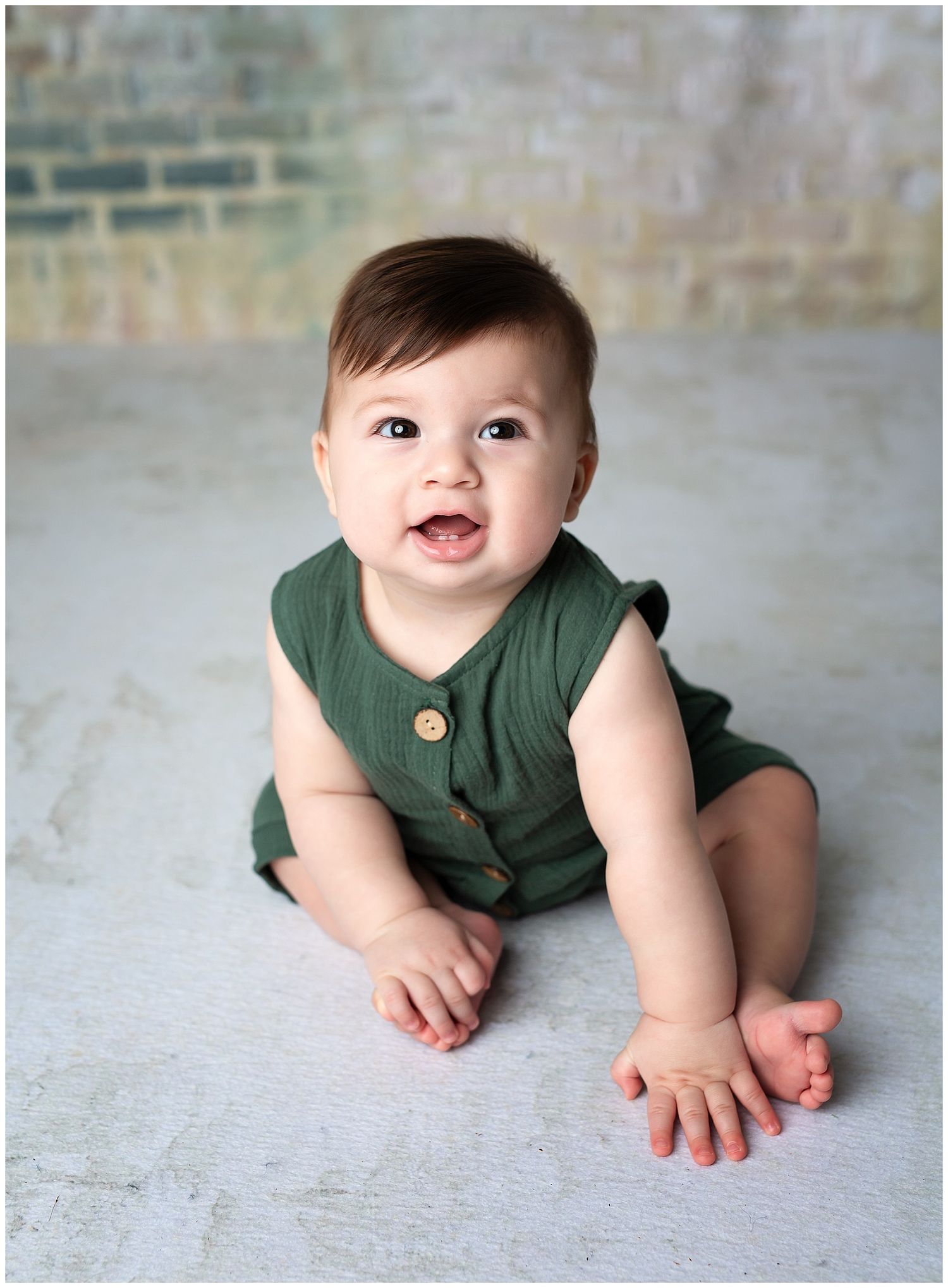 Sitting baby at Milestone Portrait Session. He is smiling and wearing green romper.  Sitter session at Austin Newborn Photography.