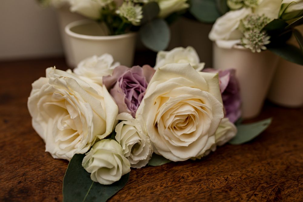 Elegant white and purple roses arranged with greenery on a wooden surface.