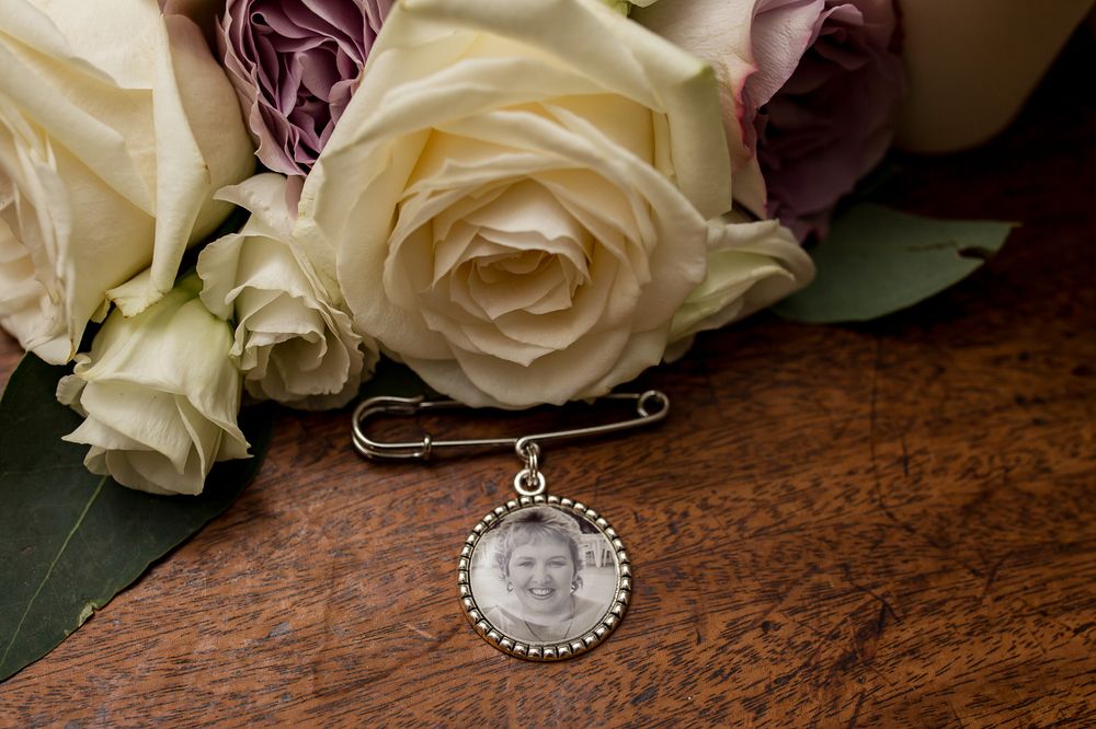 Memorial pin with roses and greenery on wooden surface.