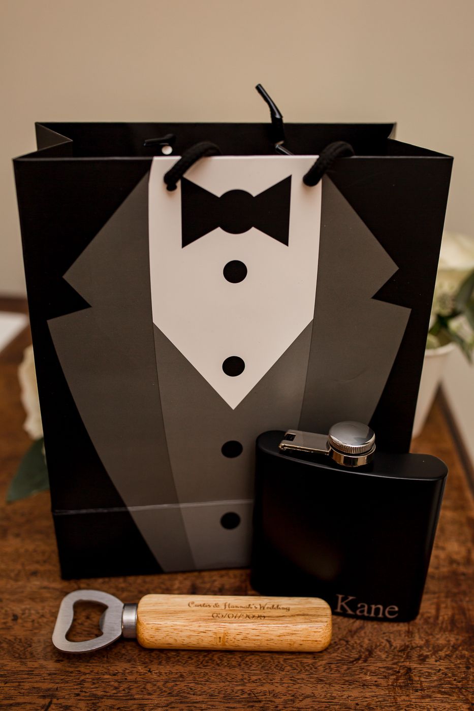 Groomsman gift set with tuxedo gift bag, flask, and wooden bottle opener.