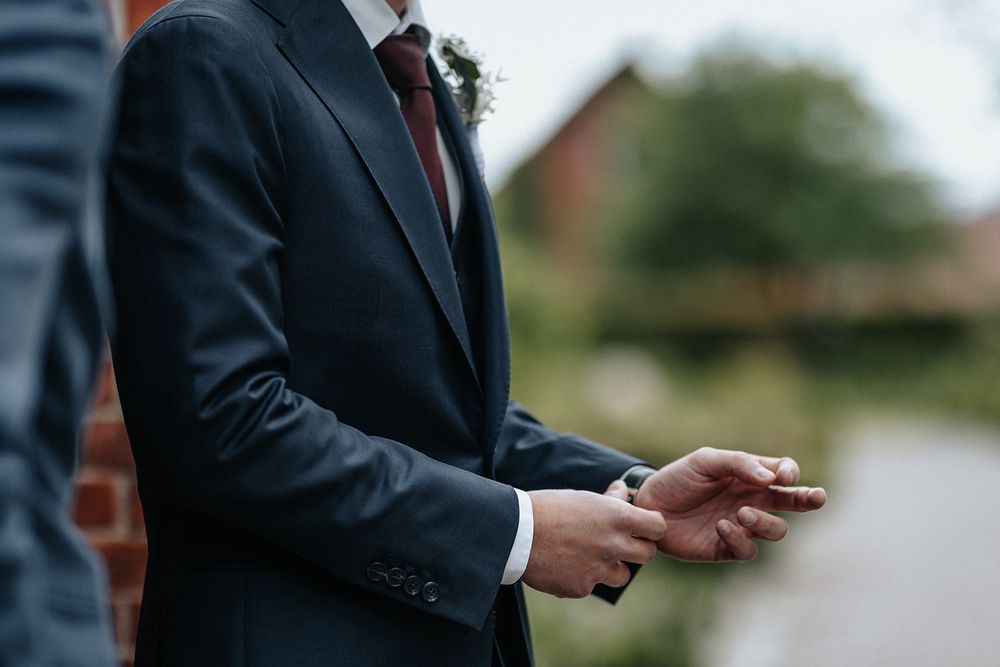 Person in a dark suit jacket gestures while speaking during an outdoor business presentation.