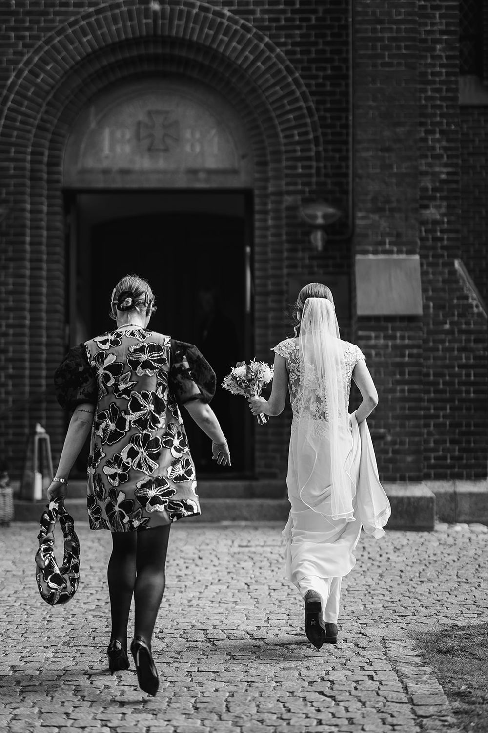 A sequence of black and white photos showing people walking on a cobblestone path near a brick building.