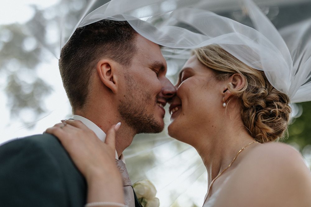 A romantic wedding couple shares intimate kisses in a series of black and white photographs outdoors.