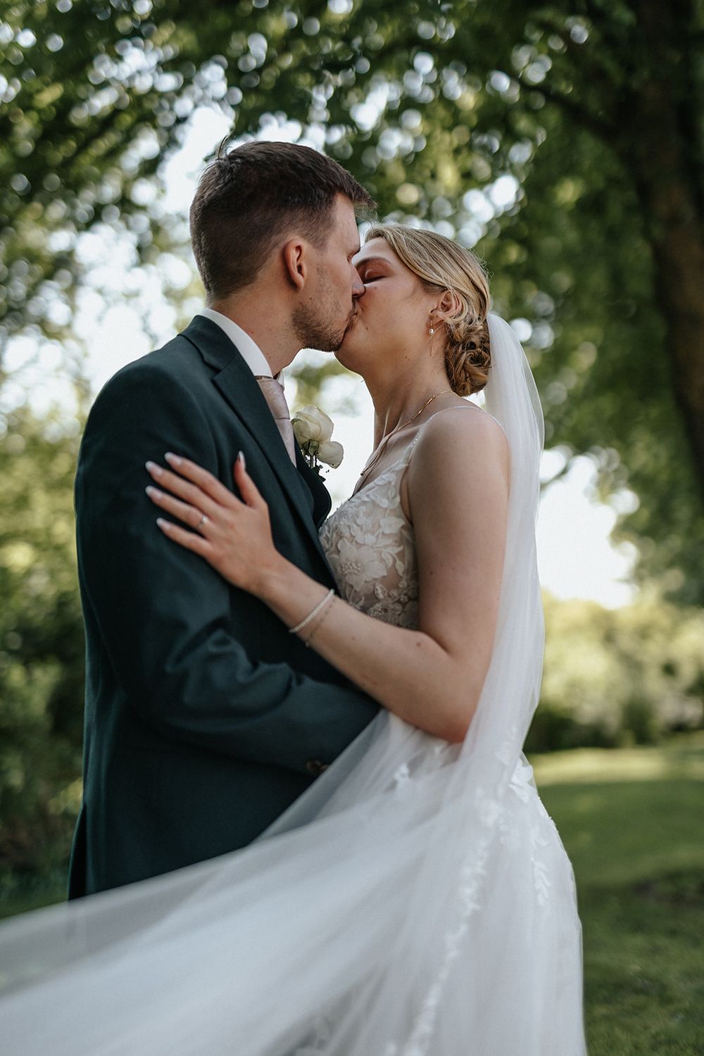 A romantic series of wedding photos showing a couple sharing a tender kiss outdoors in a natural garden setting.