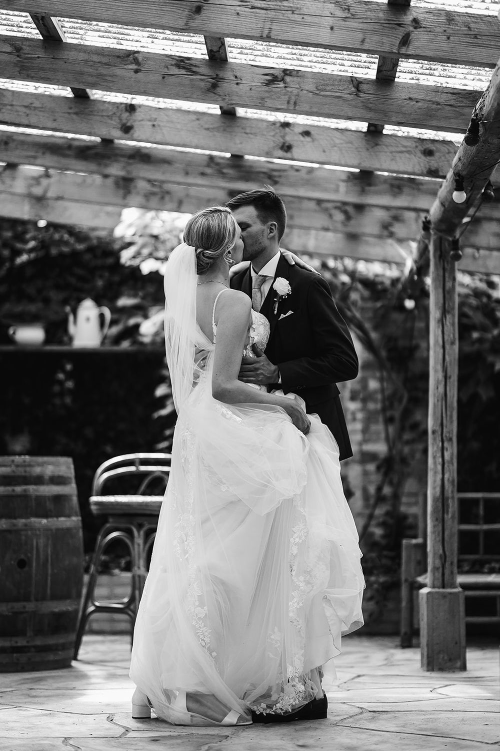 Black and white wedding photo series showing couple in romantic poses on rustic wooden deck.
