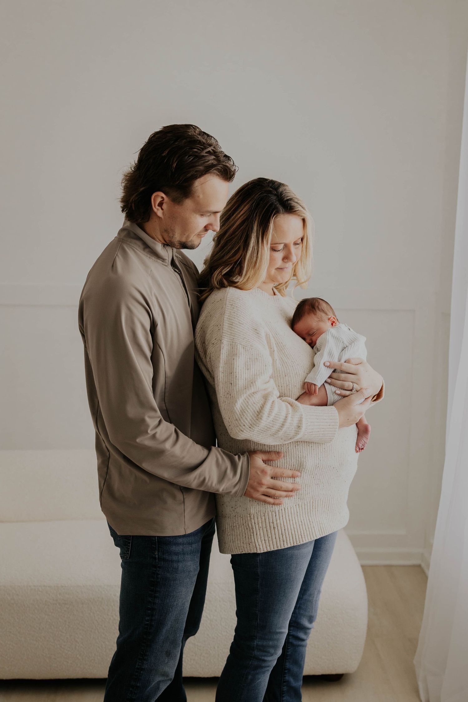 Tender Lakeville MN newborn photography session showing parents in brown and gingham outfits cradling their baby in soft natural light.