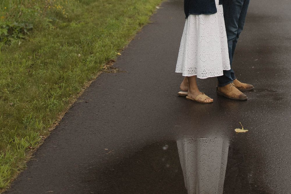 A paved pathway reflects in puddles after rain in a park setting.