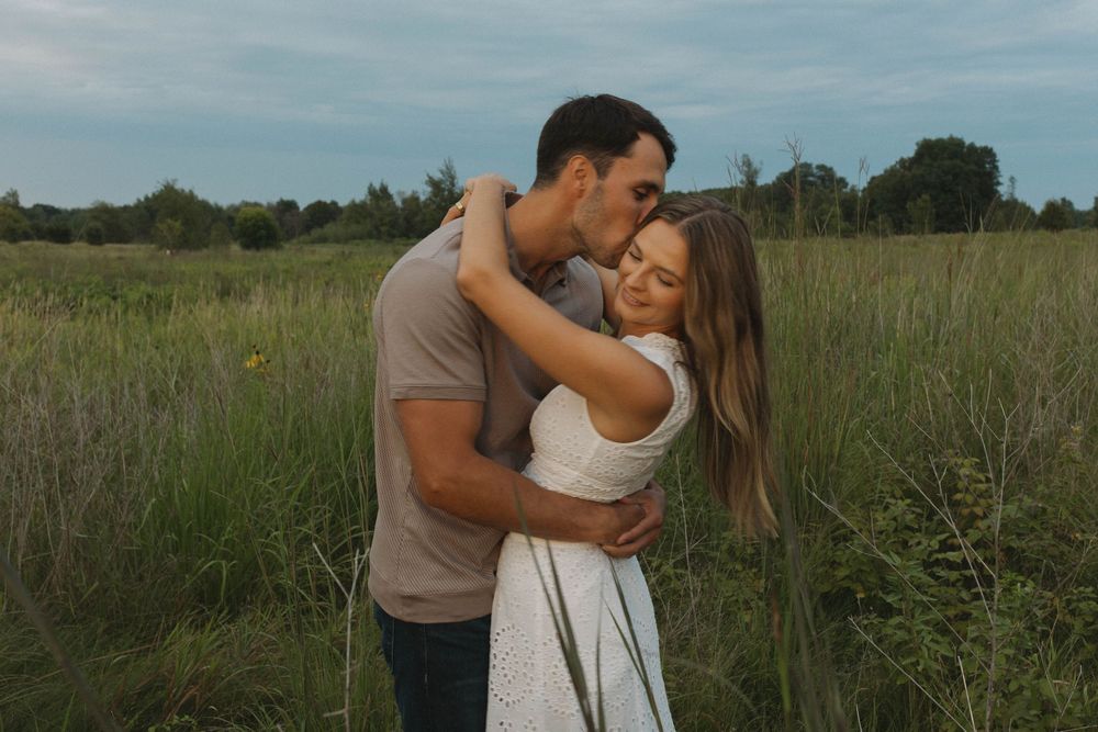 Couple embracing in golden light amidst tall grass.