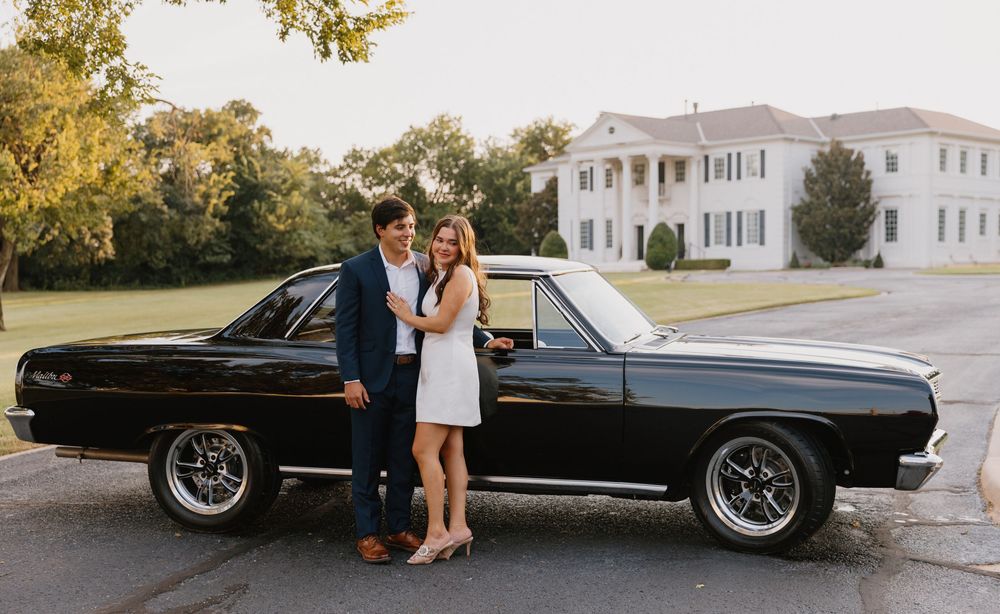 Classic black Lincoln Continental parked outdoors with white mansion in background during wedding photoshoot.