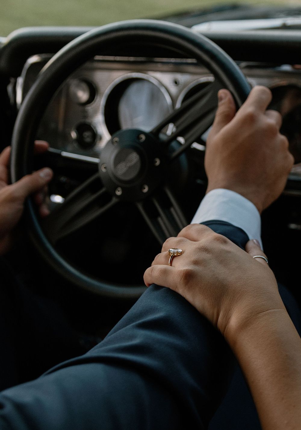 Close-up view of hands gripping a black steering wheel while driving a vehicle.