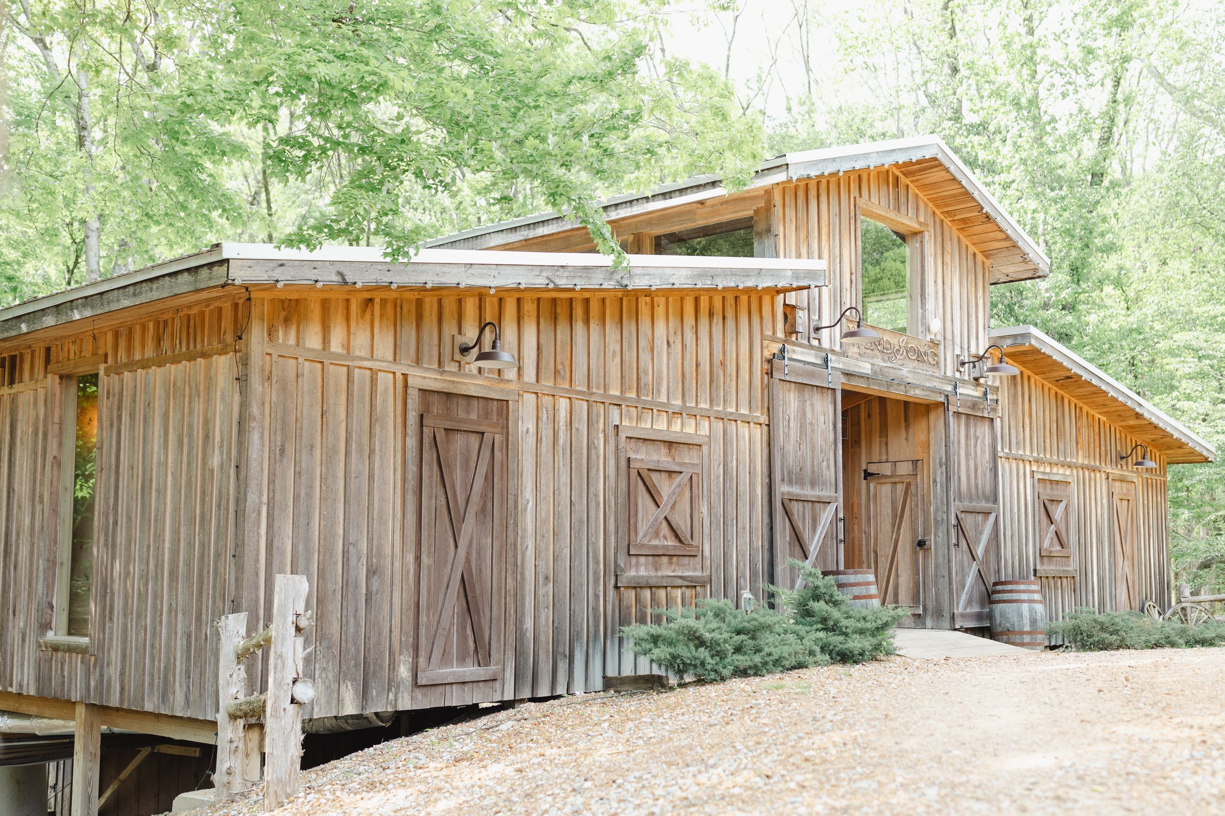 Rustic wooden barn or cabin exterior with cross-braced doors and natural wood siding in a forest setting.
