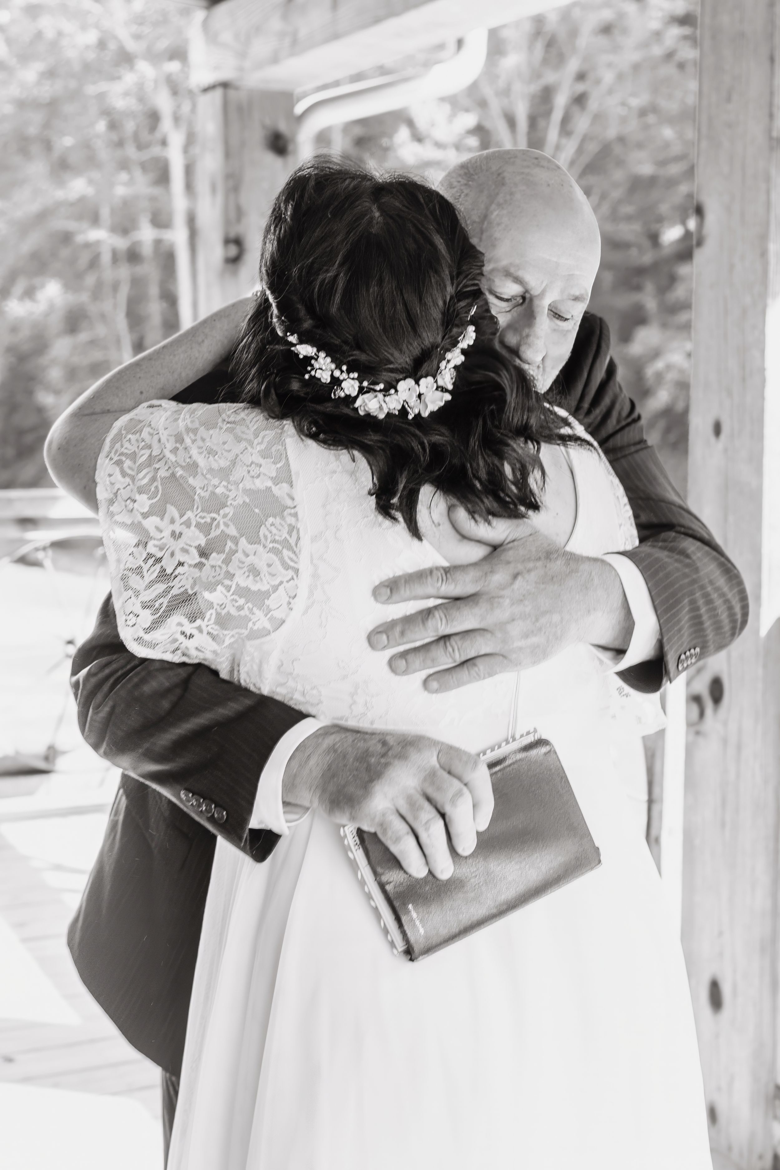 An emotional wedding moment captured in black and white showing an embrace in a rustic setting.