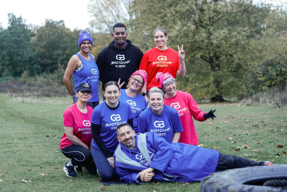 A group in blue and red shirts sits together on grassy terrain during an outdoor gathering.