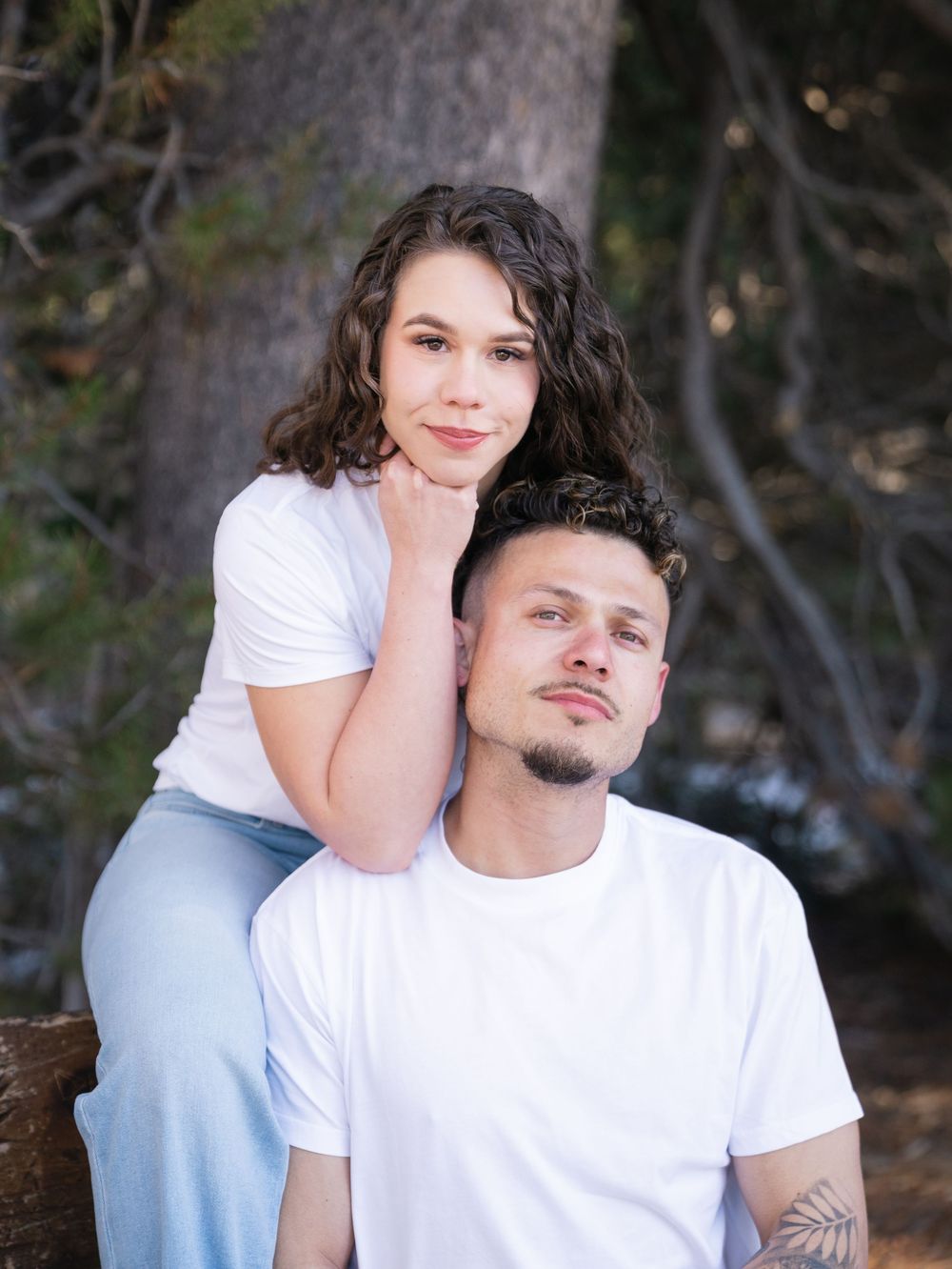 A couple poses together outdoors in casual white and blue outfits for an intimate photoshoot.