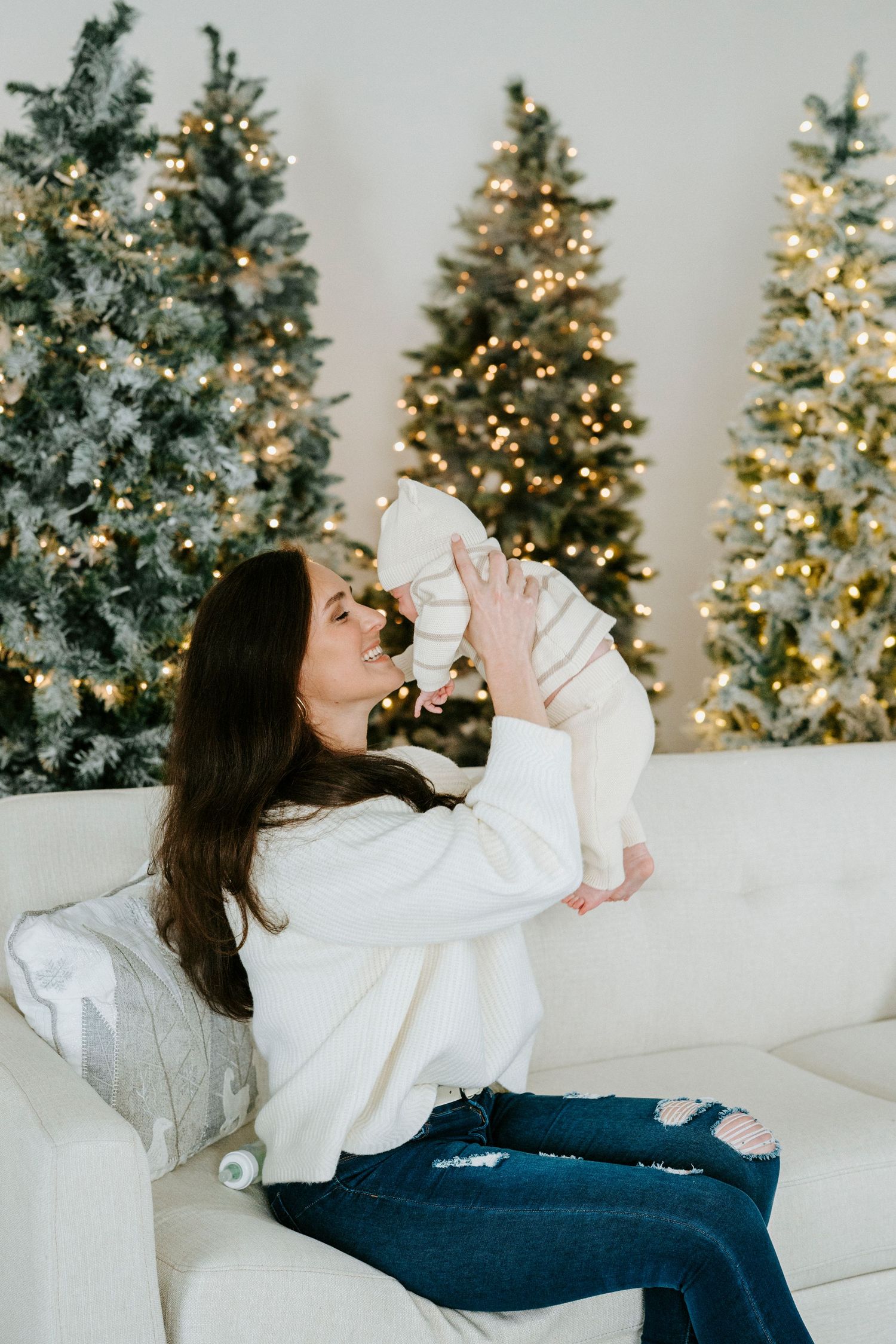 Playful lifestyle photos with lit Christmas trees and white decor showing joyful moments on a couch.