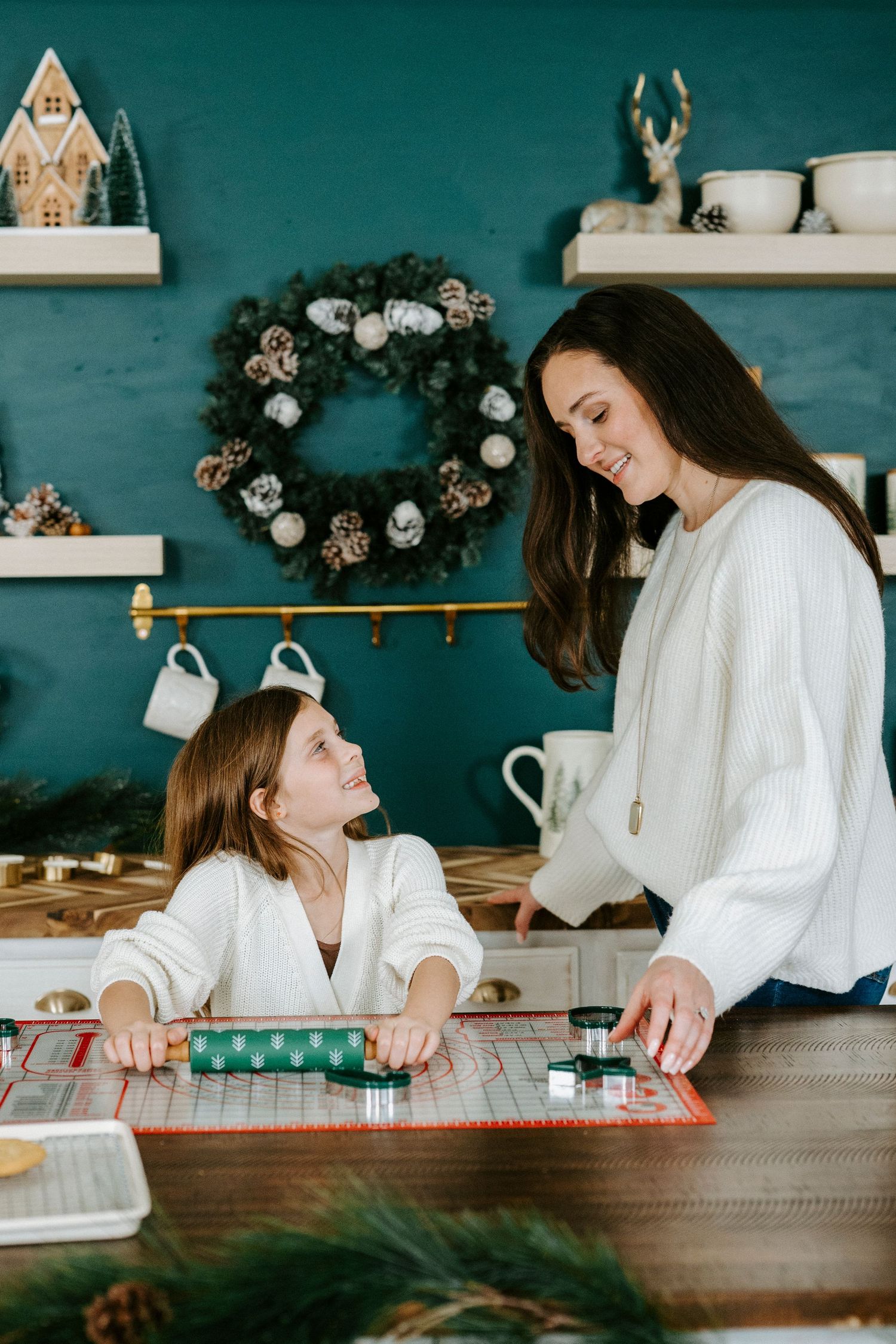 A series of candid moments showing a mother and daughter baking together at a rustic wooden counter with holiday decor.