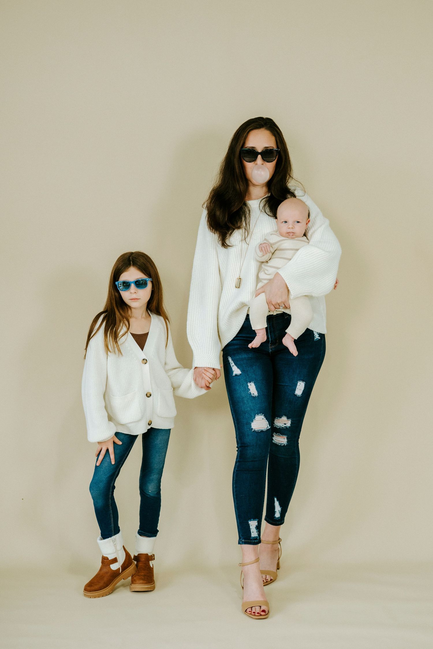 A coordinated family photoshoot featuring matching white tops and blue jeans against a neutral backdrop.
