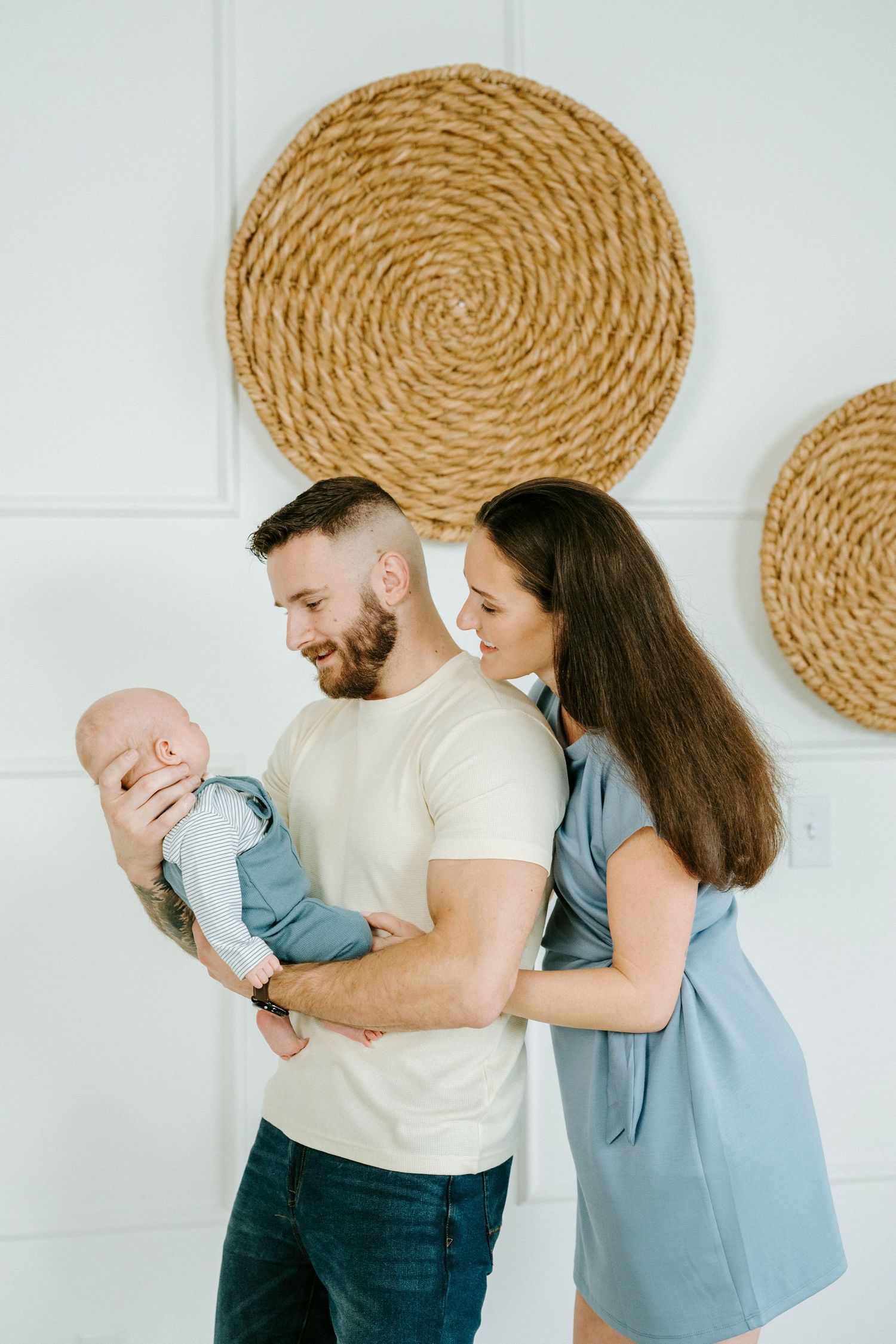 Family sharing tender moment against white wall with woven basket wall decor.