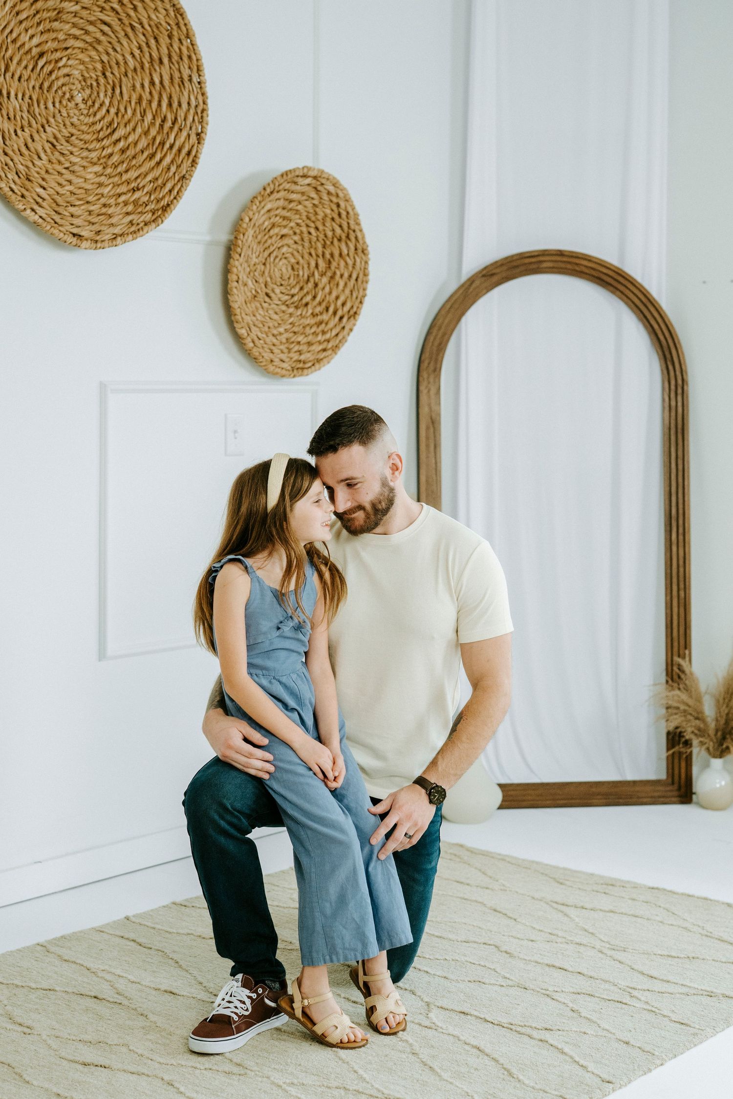 An intimate family portrait session featuring coordinated outfits in a bright white room with natural decor.