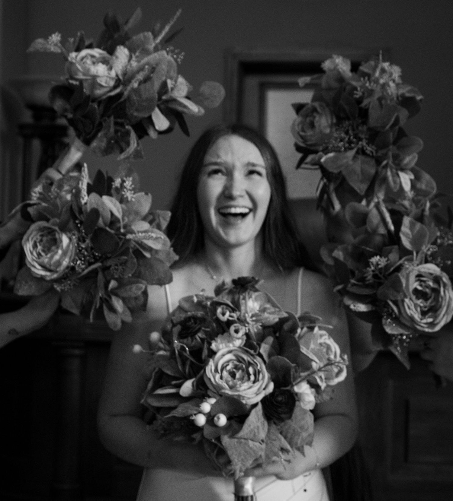 Black and white portrait of a joyful bride holding beautiful floral bouquets.
