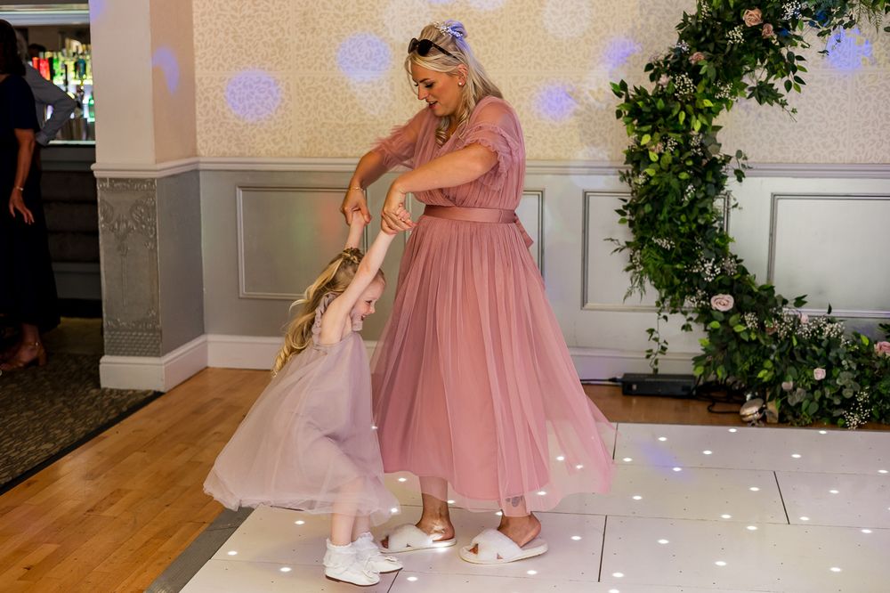 Wedding celebration on an illuminated dance floor with floral decorations and pink accents.