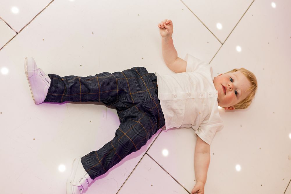 Wedding party members lying on a white dance floor with twinkling lights overhead.