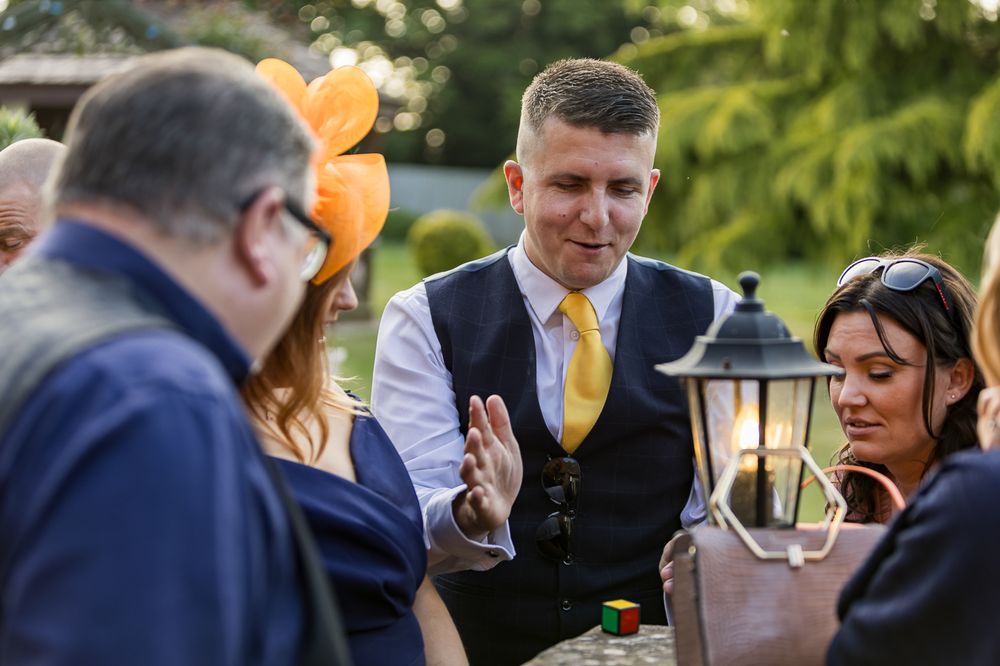 Outdoor wedding reception guests mingling during golden hour in a garden setting.