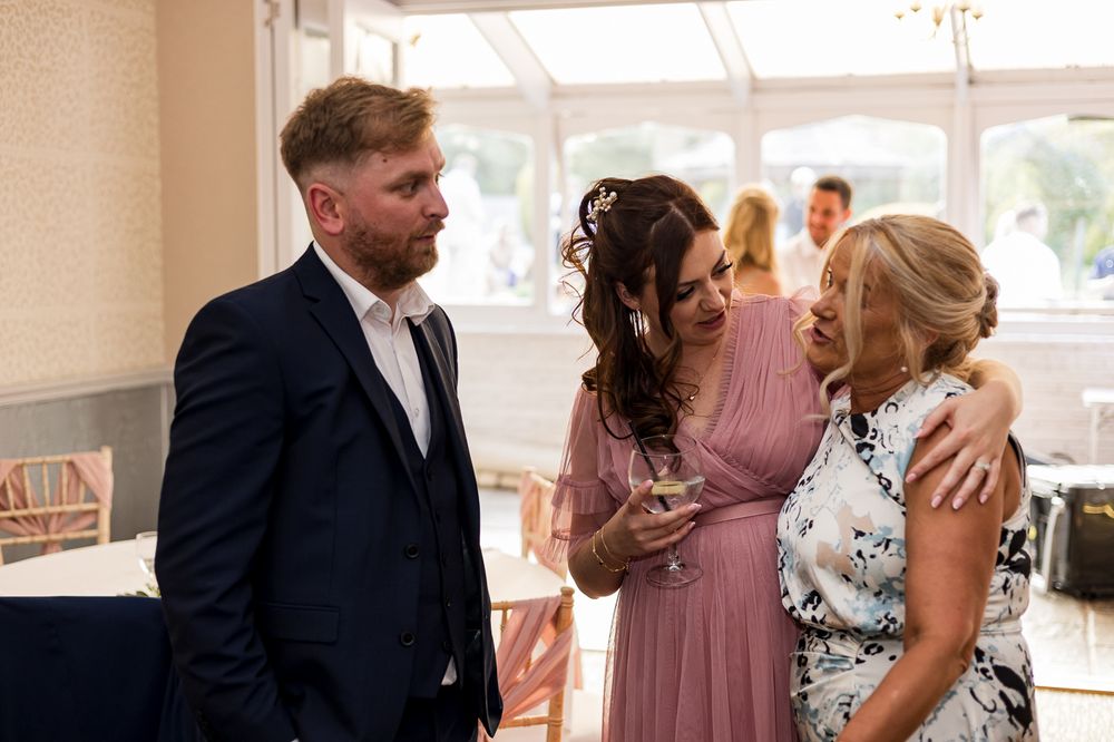 Wedding guests engage in conversation during an indoor reception.