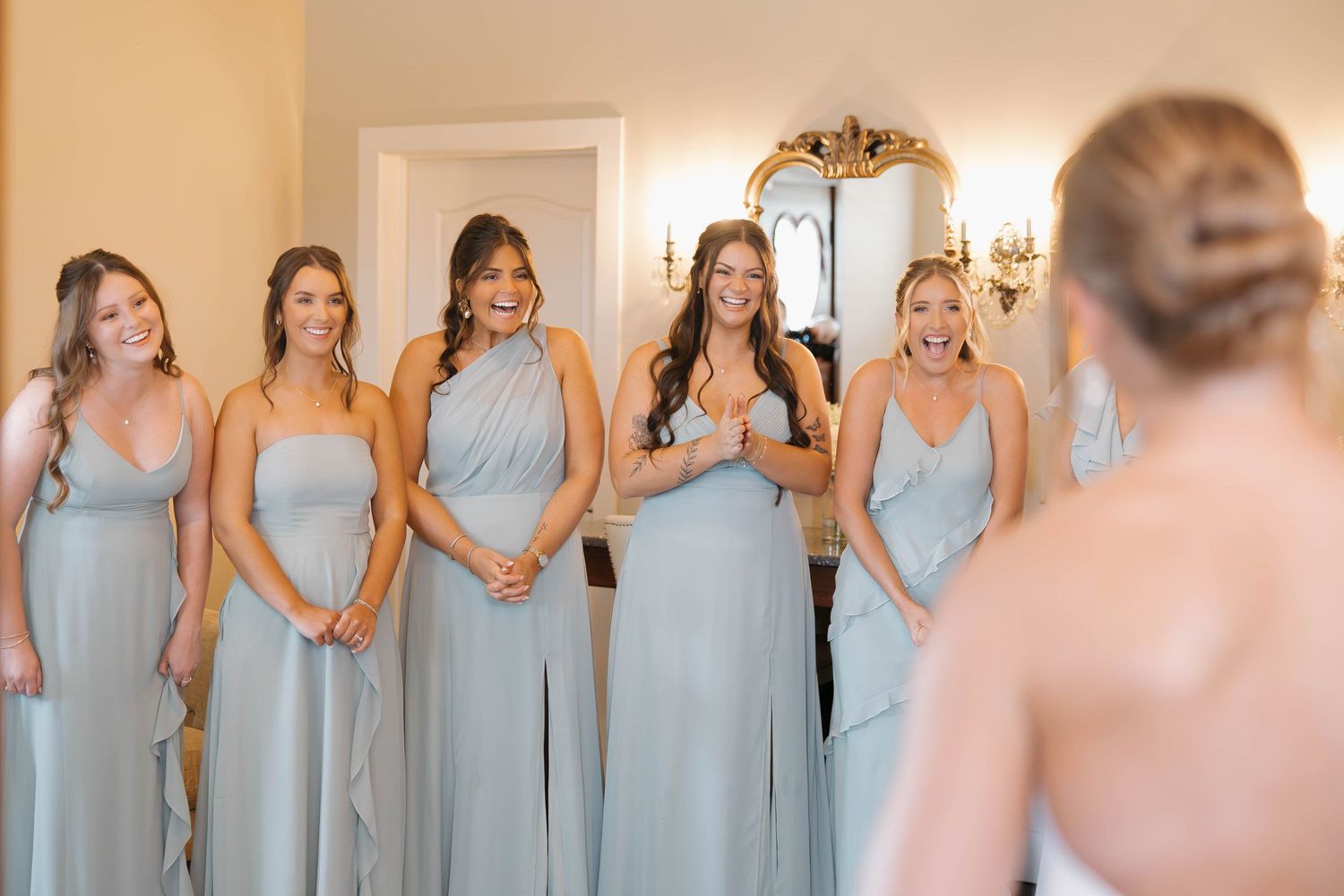 Bridesmaids wearing light blue dresses stand in a row during a wedding preparation.