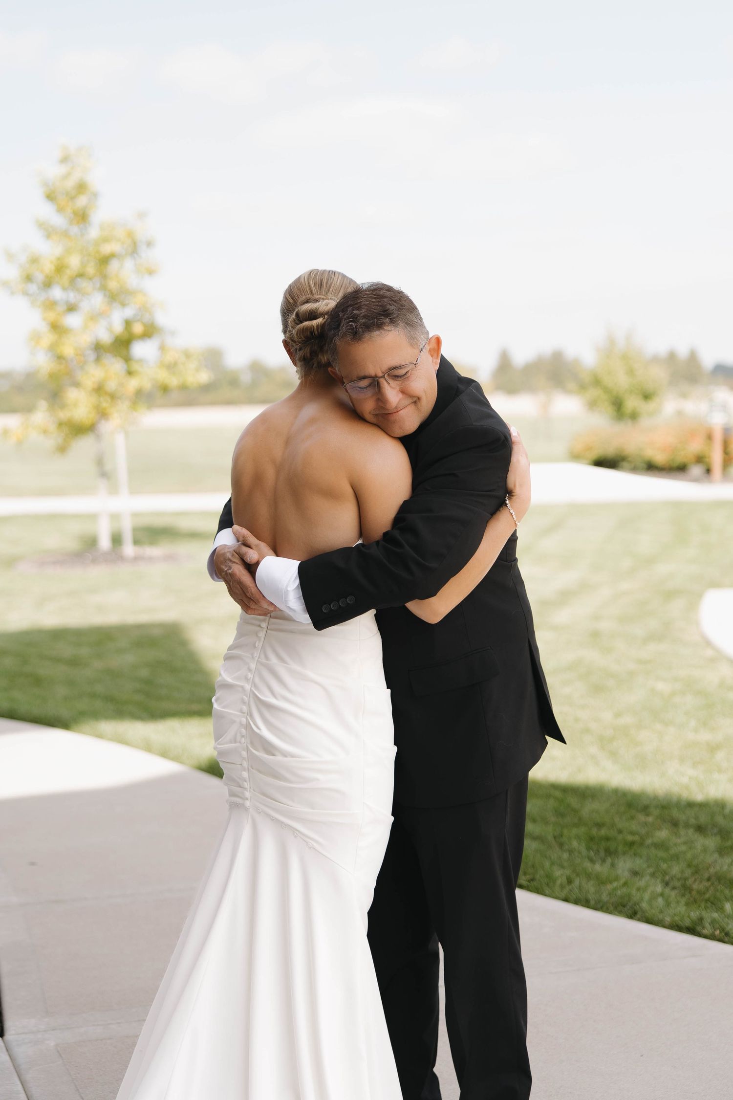 A tender embrace captured during a wedding ceremony on a sunny outdoor patio.