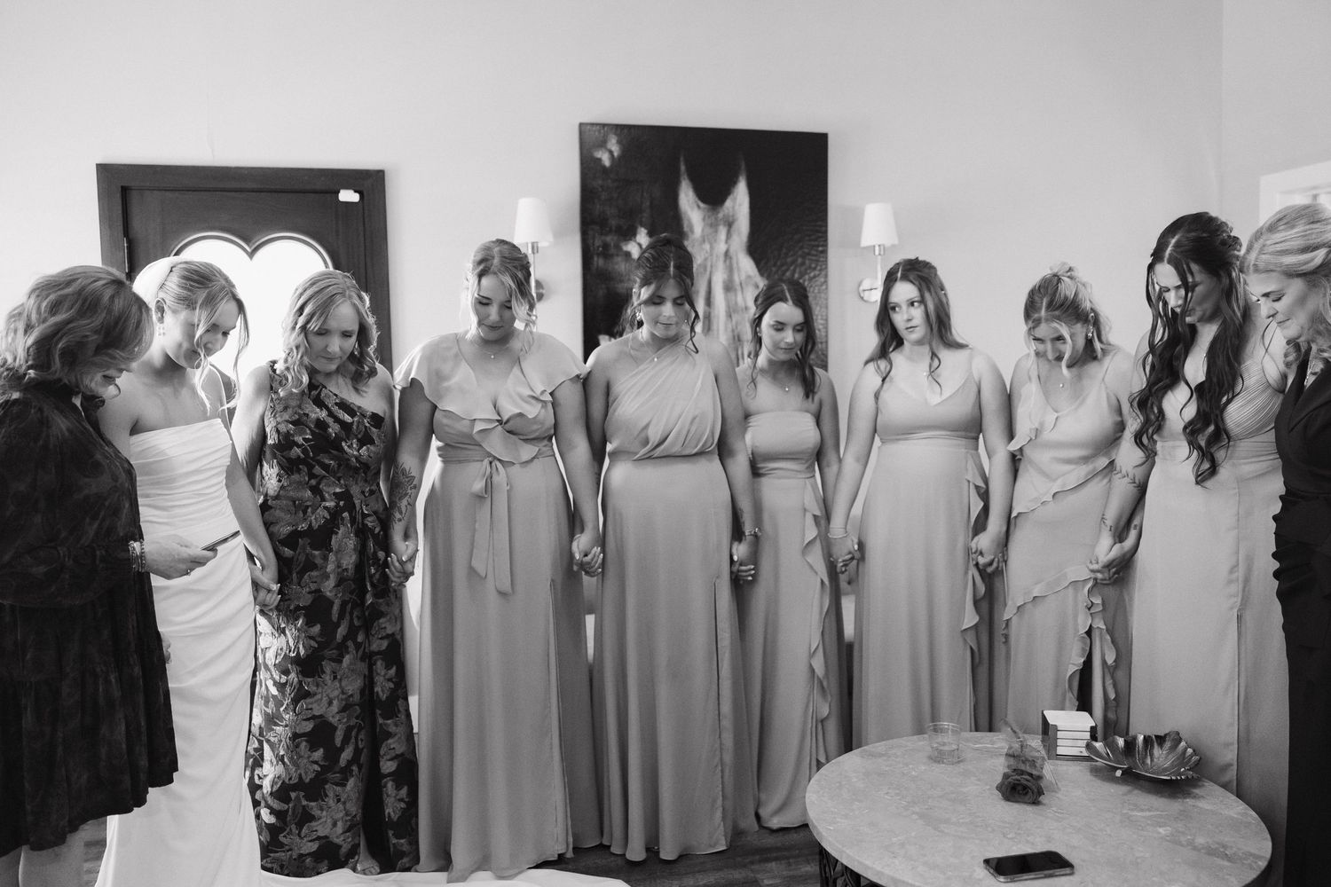 Bridesmaids wearing matching floor-length gray dresses stand together in a row during a wedding celebration.