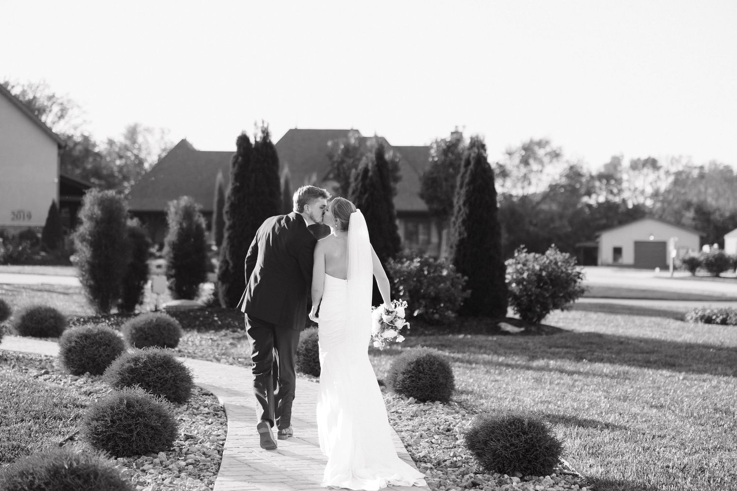 A black and white photo of a couple walking together on a garden pathway.