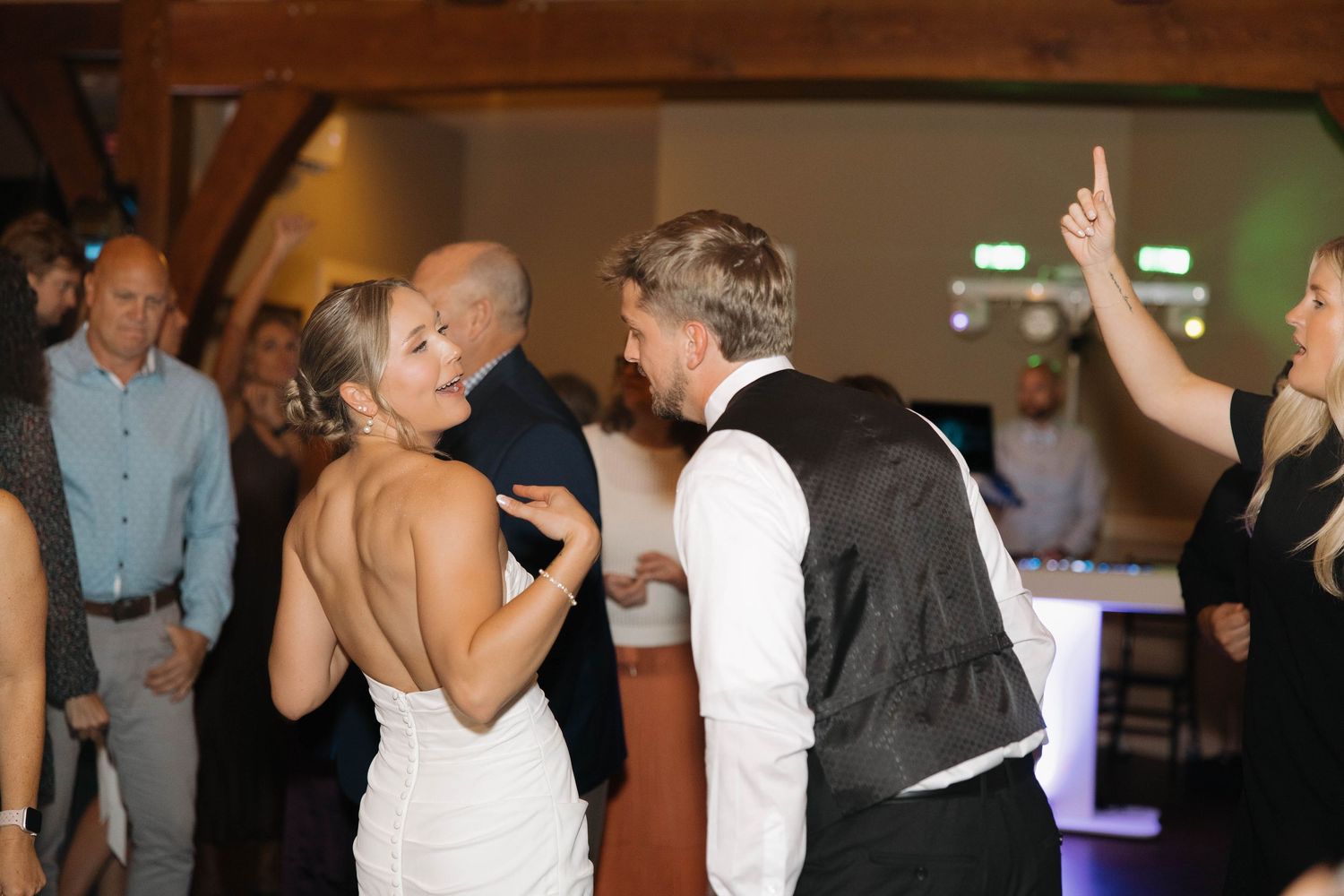 A couple dances together at a wedding reception while guests watch from the background.