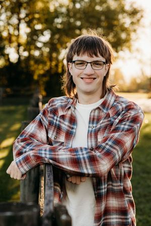 Casual outdoor portraits against wooden fence and autumn foliage in warm evening light.