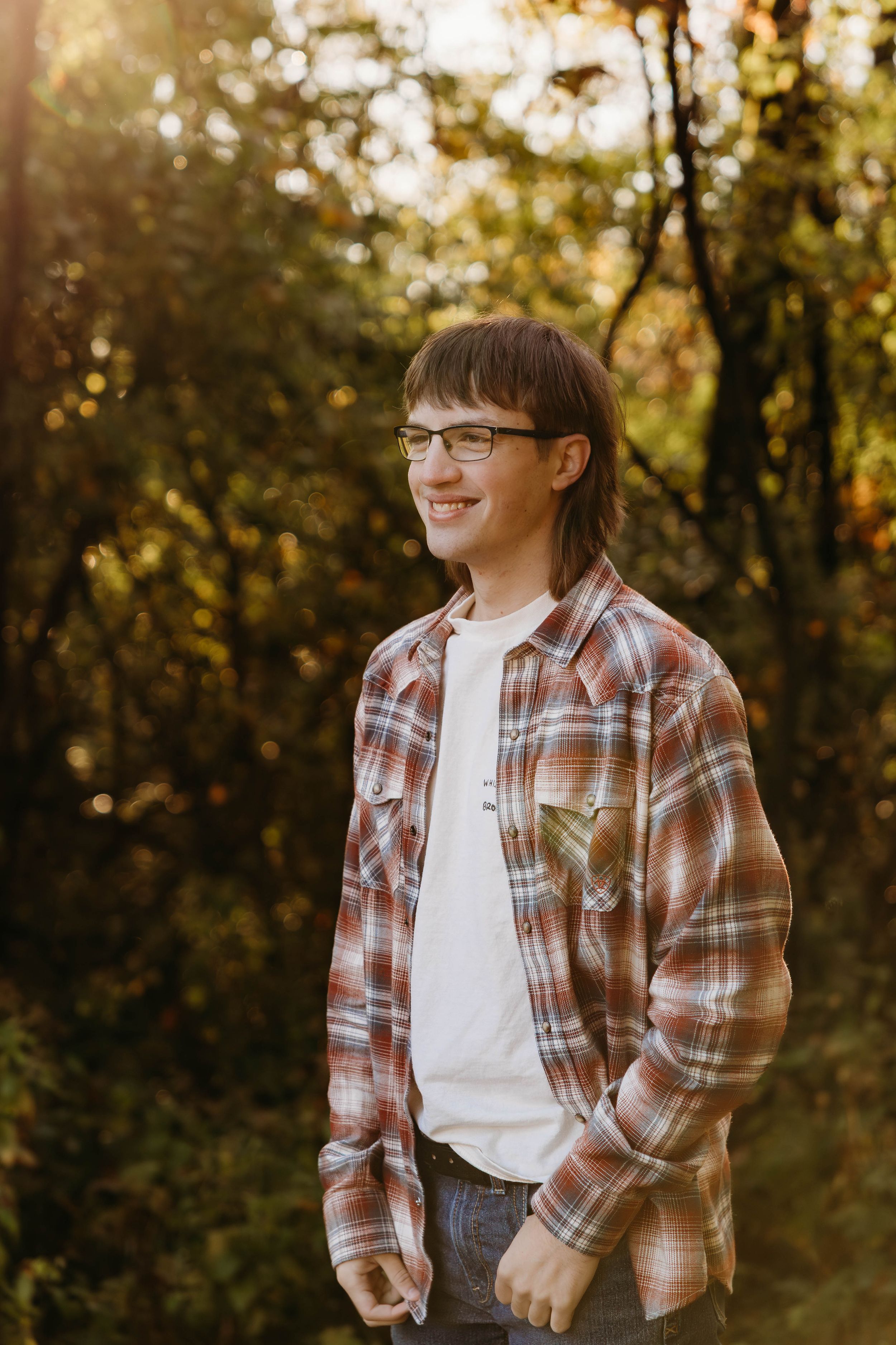 A series of warm autumn portraits showing someone in a plaid flannel shirt and glasses against a sunlit forest backdrop.