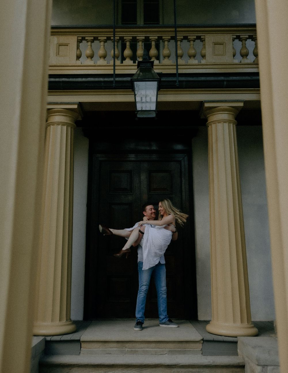 A couple poses playfully across three connected architectural frames with cream-colored columns and arches.