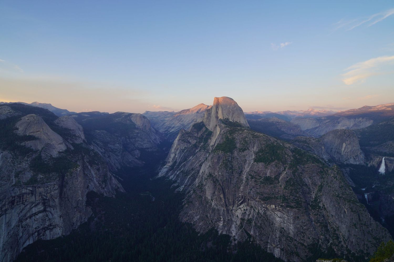 Panoramic view of Yosemite Valley at sunset showcasing Half Dome and surrounding granite cliffs.
