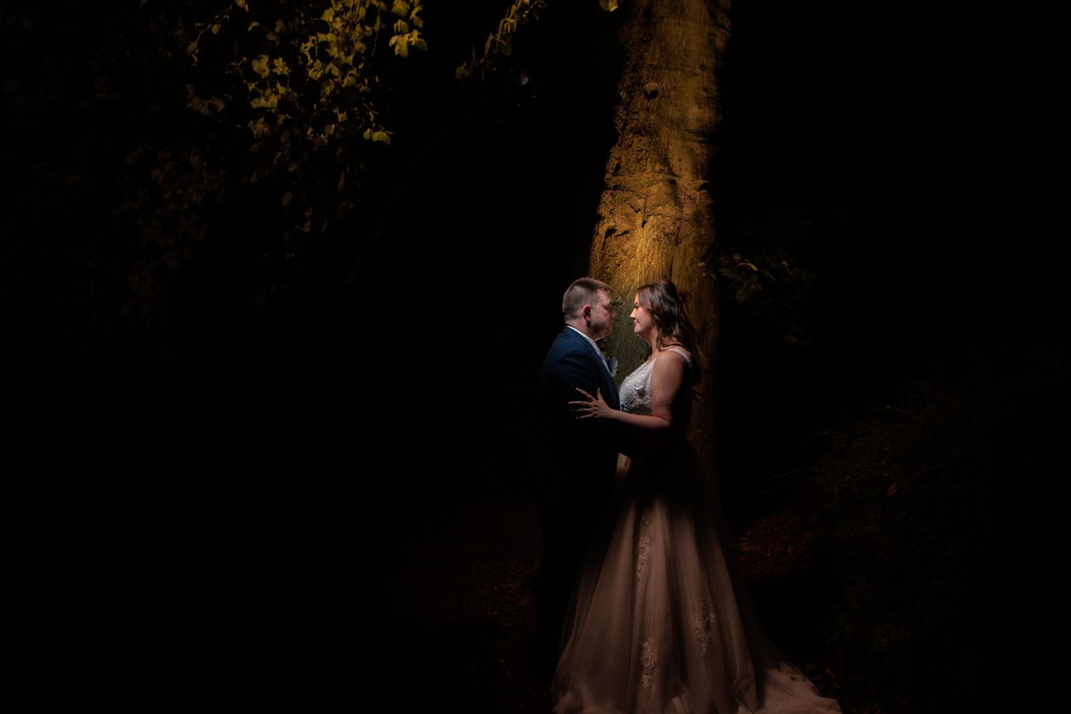 Elegant bride and groom share a romantic moment during their outdoor wedding photoshoot at sunset.
