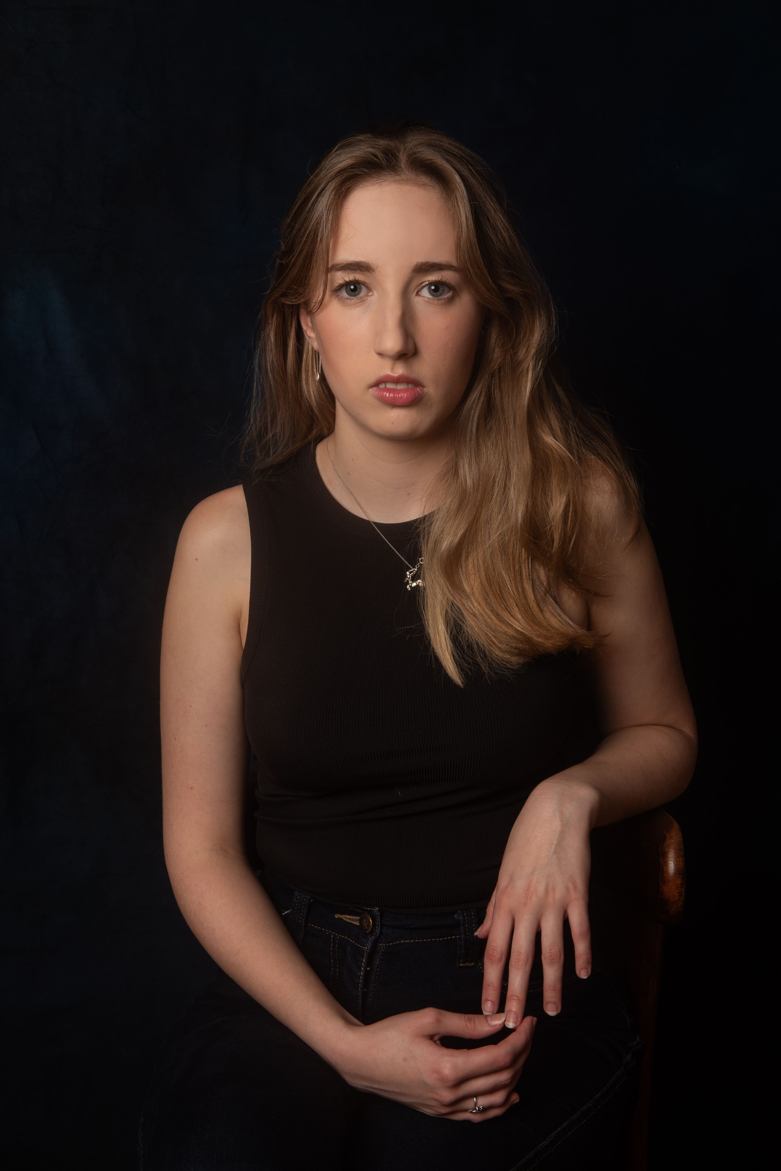 Studio portrait of person in black top against dark background.