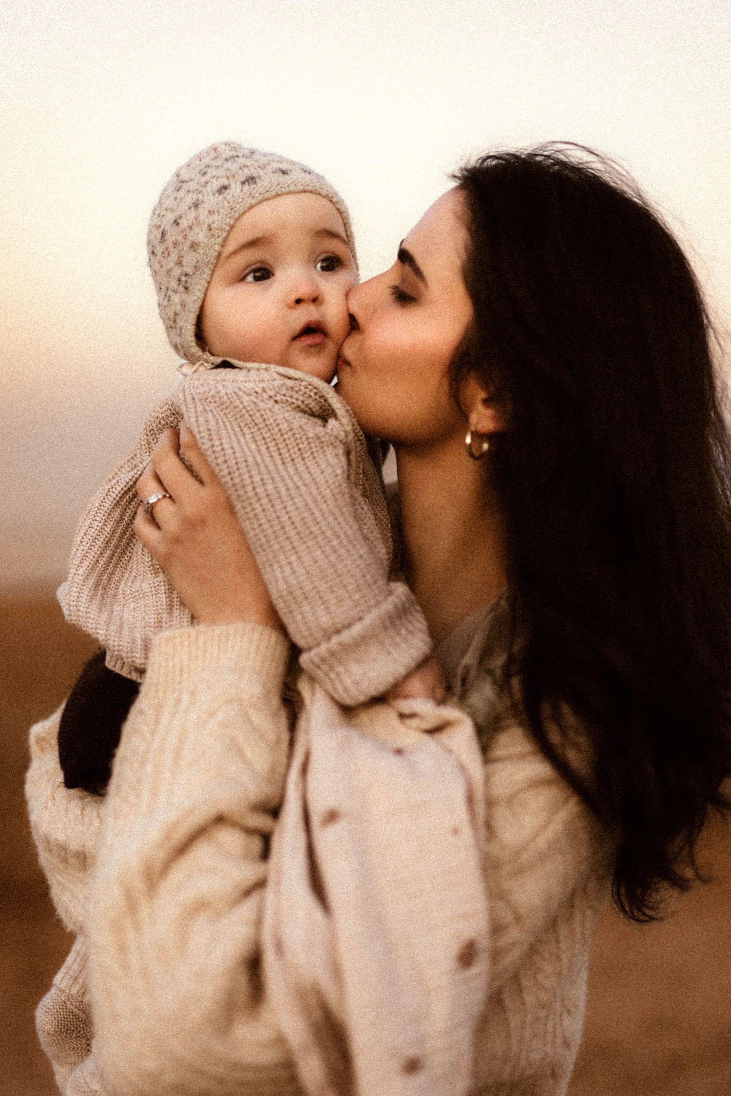 A tender moment between parent and child in Javea, wearing cozy winter knits in warm sepia tones. Javea photographer