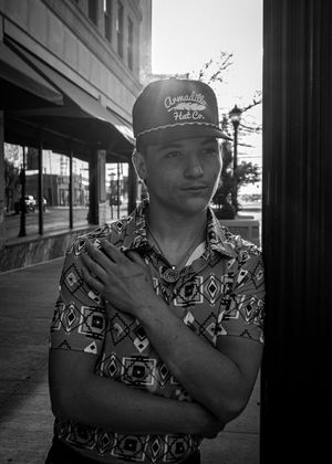 Urban street portrait of person in patterned shirt and baseball cap.