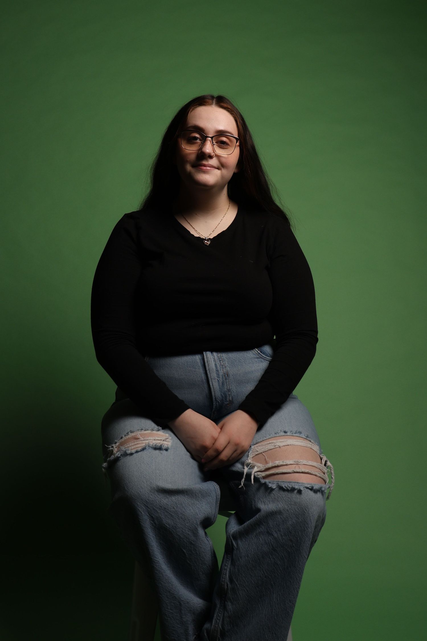 Brown haired girl waist up in front of green background